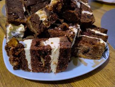 Beyaz kremayla kaplı çikolatalı pasta, porselen bir tabakta yatıyor..