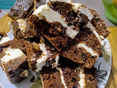 Beyaz kremayla kaplı çikolatalı pasta, porselen bir tabakta yatıyor..