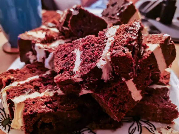 Beyaz kremayla kaplı çikolatalı pasta, porselen bir tabakta yatıyor..