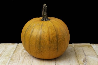 Tahta masadaki siyah arka planlı turuncu balkabağı.