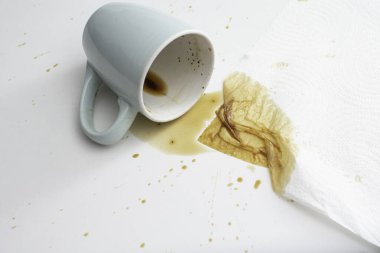 Beyaz arka planda, emici kağıt havlu parçasıyla bir fincan kahve döküldü. Yumuşak odak kapat