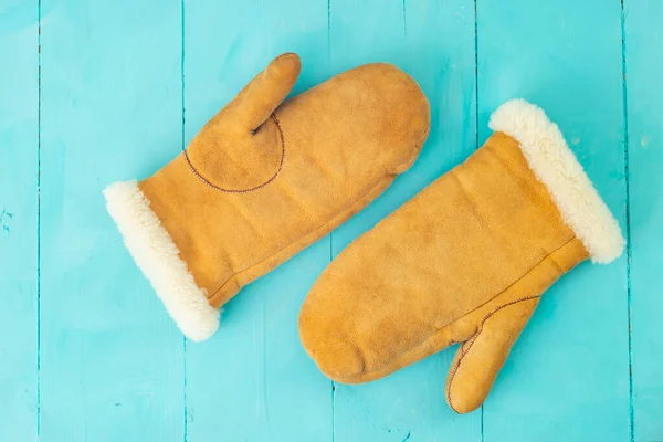 Suede mittens on blue wooden boards, soft focus close up
