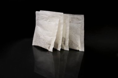 4 paper tea bags isolated on black background with reflection, close up