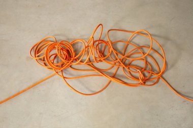 Tangled orange electrical cord, impossible problem concept 