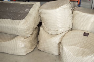 Furniture bubble wrapped ready to be shipped, on cement floor, abstract textures