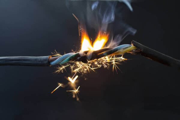 flame smoke and sparks on an electrical cable, fire hazard concept, soft focus close u