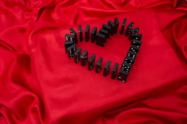 Stock image Domino tiles forming a heart shape on red satin fabric, love and passion background