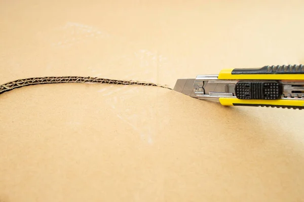 stock image Steel blade cutter cutting thru cardboard, soft focus close up