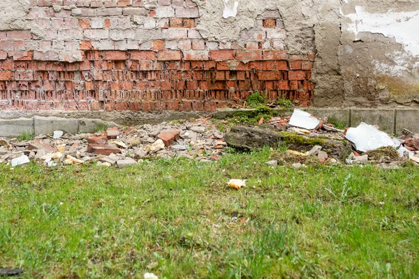 Collapsing wall due to water infiltration, red brick wall deteriorated and green grass