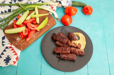 Kebapche Cevapcici ya da mici, mavi boyalı ahşap tahtalarda sebzeli mititei