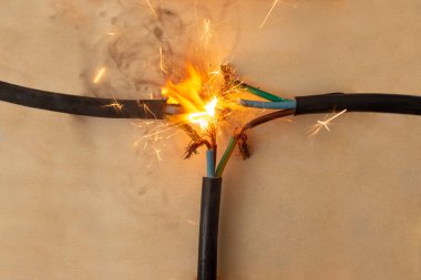 Alev dumanı ve kıvılcımlar üç elektrik kablosunda hatalı bağlantı, ahşap arka plan, yangın tehlikesi kavramı, yumuşak odaklanma
