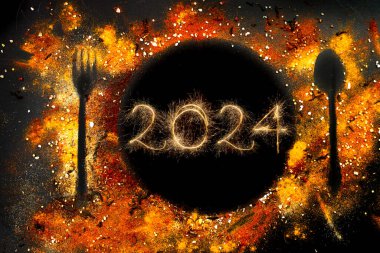 Tabak silueti, kaşıkla çatal ve baharatlarla yapılmış koyu arkaplan. Kıvılcımlarla yazılmış 2024, yeni yıl partisi  