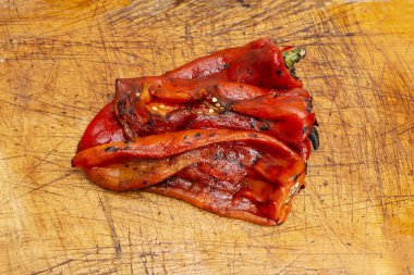 ızgara kavrulmuş ve soyulmuş kırmızı biberler ahşap doğrama tahtasının üzerinde