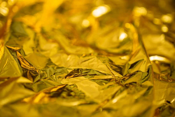 Defocused golden tin foil, abstract holiday backdrop, soft focus