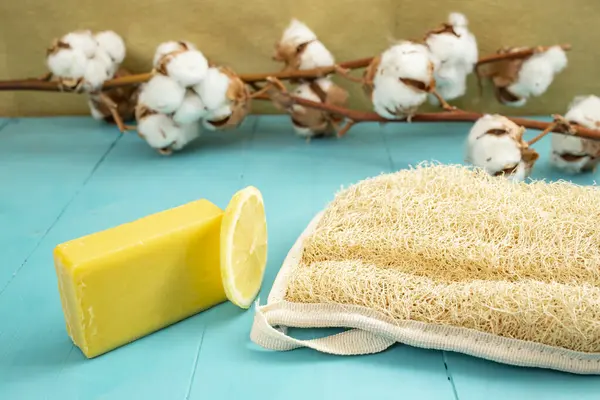 Limon sabunu ve limon dilimi pamuk tomurcukları çiçekleri ile banyo lifinin yanında, yan görünüm fotoğrafçılık.