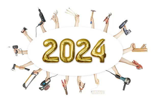 2024 yılının yeni yılı için altın balonlardan, nalbur bayramı tabelasından yapılmış birden fazla alet tutan eller.  