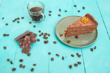 Çikolatalı kakaolu kek dilimi ve mavi ahşap bir masada kahve çekirdekleri.