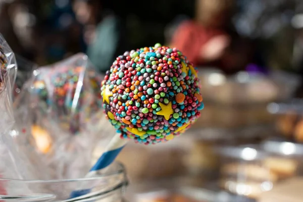 Chocolate lollipop on a stick exposed at a autumn fair market, soft focus close up
