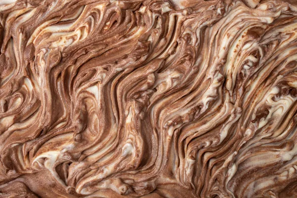 White and brown chocolate cream swirls on a birthday cake, top view abstract backdrop