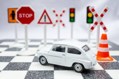 Satranç tahtasında trafik işaretleri olan küçük beyaz model bir araba, sürücü ehliyeti konsepti, yumuşak odaklı.  