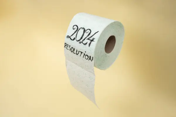 2024 resolution written with black ink on a toilet paper roll. levitating on beige color background
