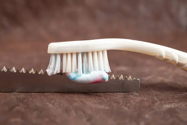 Tooth brush and paste on a saw, on leather background , soft focus