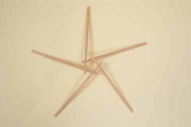Bamboo wooden sticks demonstrating a pentagram reciprocal frame structure, on beige   clipart