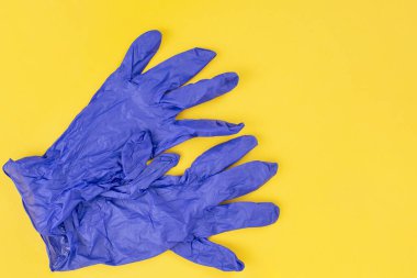 Sarı arka planda mavi lateks cerrahi eldivenler, soyut  