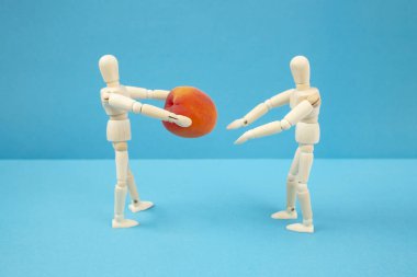 İki ahşap manken, biri şeftali meyvesi tutuyor, bağış konsepti, yumuşak odaklı.  