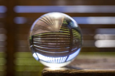 Kristal küreyle optik bozulma, tahta çitler, yeşil çimenler ve mavi gökyüzü. 