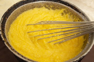 Dökme demir bir tencerede mısır unu kaynatmak, mamaliga yapmak, geleneksel Romanya yemekleri, ve paslanmaz çelik çırpıcı ile karıştırmak, yumuşak odak  