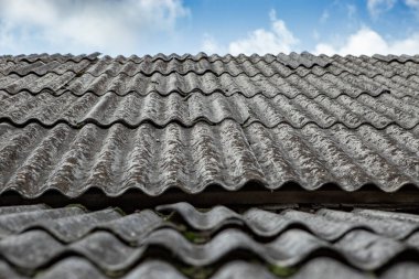 Ev odasındaki gri asbest çarşaflar, mavi gökyüzü manzaralı. 