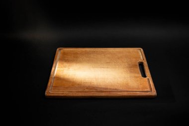 Minimum mutfak arkaplanı dikdörtgen ahşap kesim tahtası ve ışık ışını, siyah üzerine.  