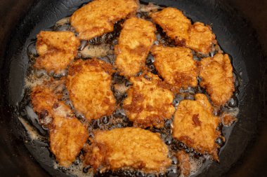 Tavuklu göğüs eti fileto tavada kaynamış yağda yumurta, düz yatıyordu.  