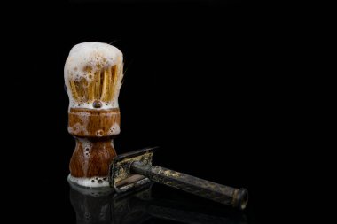 Fırçada sabun köpüğü ve eskimiş jilet siyah üzerine izole edilmiş.  