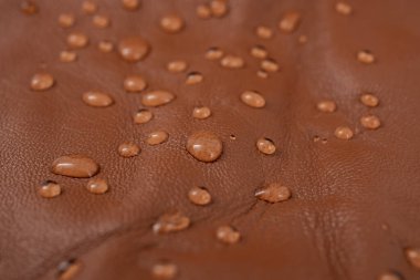 Round water drops on red brown leather texture, top view, soft focus close up   clipart