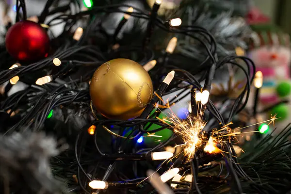 Plastik bir noel ağacında yılbaşı mum ışıkları, kısa devre kıvılcımları, yumuşak bir odaklanma...,  