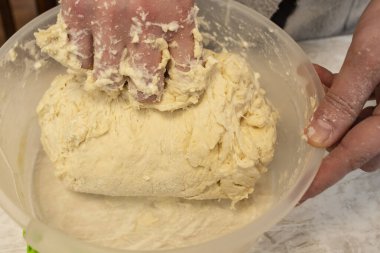 Kadın elleri plastik kasede hamuru karıştırıyor., 