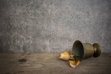 Yıpranmış ahşap tahtada kurumuş bir gül ve gri çimento kaplı duvar arkaplanı, soyut klasik fon.