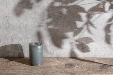 Çimento desenli duvar, aşınmış ahşap masa ve ağaç yaprakları gölgeler, gri mum, kopyalama alanı  