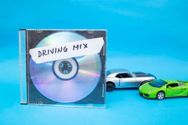 Mavi arka planda oyuncak arabaların yanında küçük disk ve kasete yazılmış karışık sürüş sözcükleri  