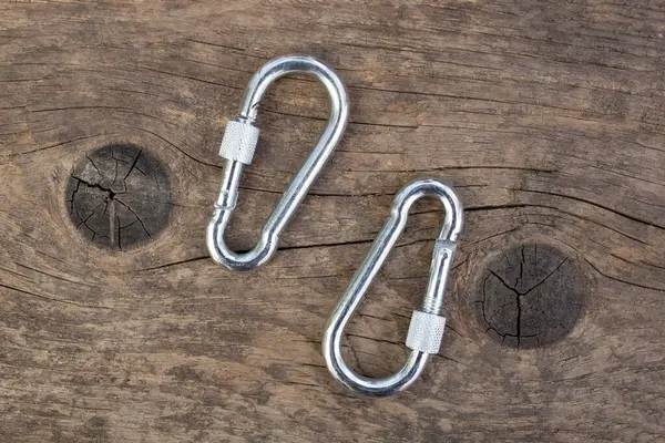 Yıpranmış ahşap arka planda iki gümüş çelik karabina.,  