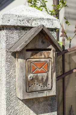 Çit kazığında eski ahşap bir posta kutusu vardı. 