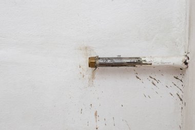Beyaz sıva duvarına kirli su sıçrayan metal boruyu kes, ısıtma bağlantısı koptu.  