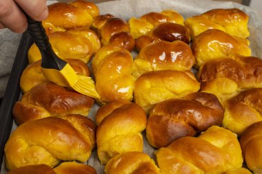 Sfintisori 'ye bal şurubu süren mutfak fırçası. Romanya mutfağı. Ev yapımı Mucenici, geleneksel tatlılar. Şekil 8, bal sürülmüş.  