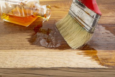 Ahşabı keten tohumu yağı fırçasıyla mühürlemek meşe ağacı desenli kare bir şişeden yayılır.  