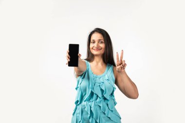 Portrait of a smiling Mid aged Indian woman holding smartphone over white background
