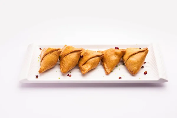 Indian sweet samosa is a Fried pastry soaked in sugar syrup filled with coconut, nuts and fruits