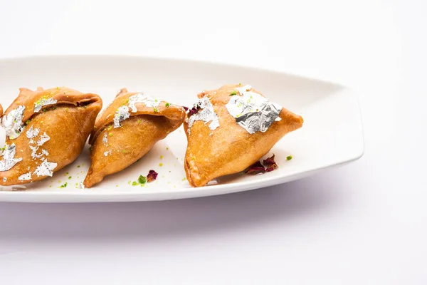 Indian sweet samosa is a Fried pastry soaked in sugar syrup filled with coconut, nuts and fruits