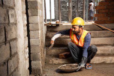 Tuğla duvar ören mutlu Hintli erkek inşaat işçisi - sıkı çalışma konsepti, el işçiliği